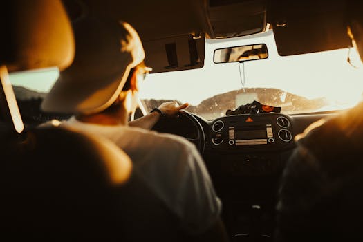 Home Man driving car with passenger at sunset, capturing warm sunlit atmosphere.